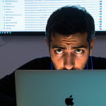 **Prompt:** A concerned Italian citizen sitting at a table covered in open data reports (Open Data Italia logo visible), illuminated by the glow of a laptop screen displaying a complex algorithm. Emphasize data privacy, GDPR compliance, and the feeling of empowerment through digital literacy. A worried expression should show on the citizen's face.